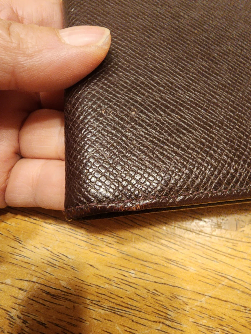 burgandy Louis Vuitton Taiga leather bifold wallet featuring a debossed LV